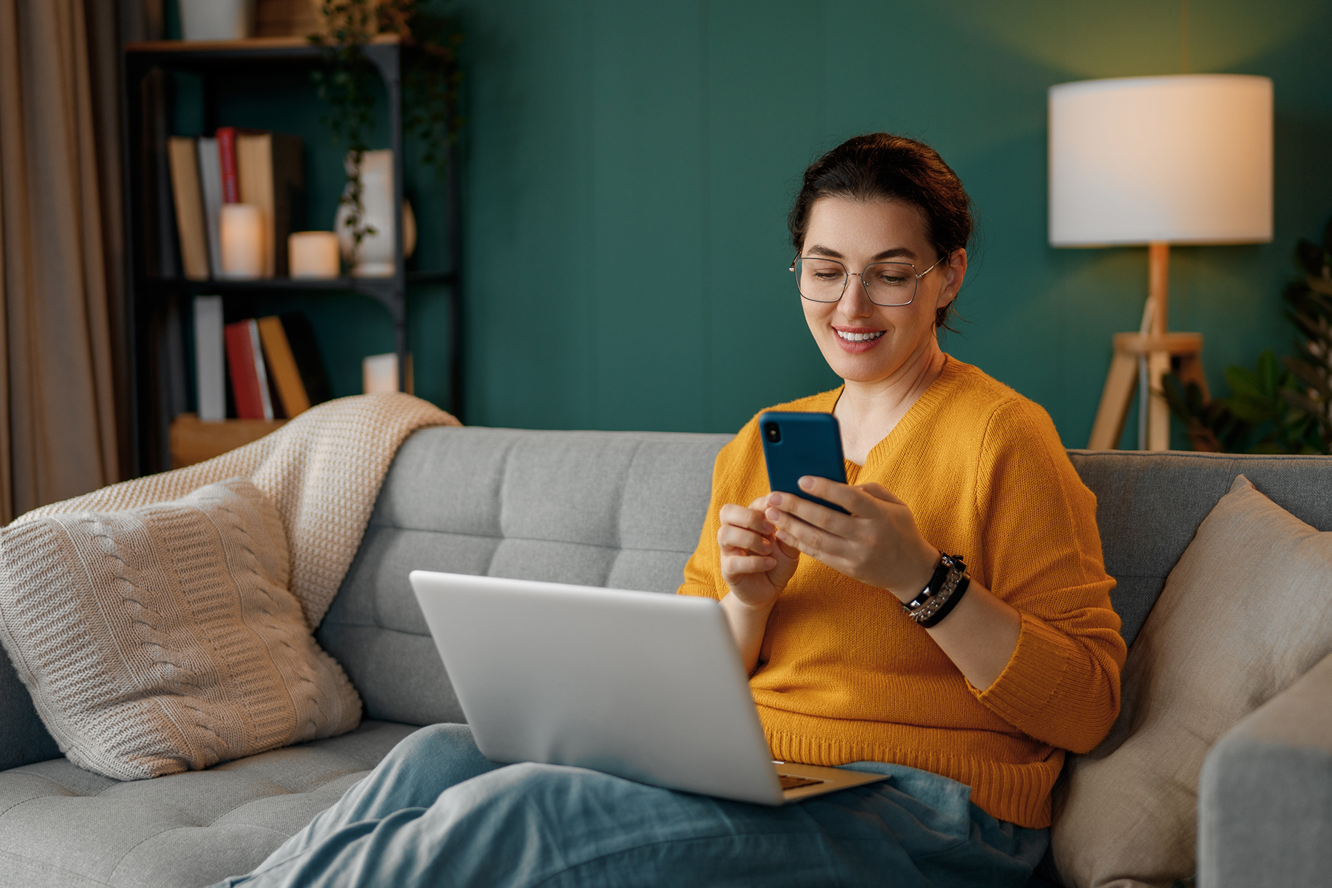 Happy woman reviewing research results on her phone and laptop